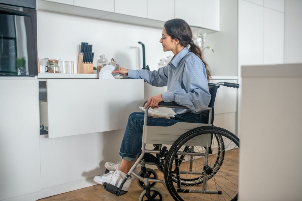 A young girl on a wheelchair doing some housework and looking involved